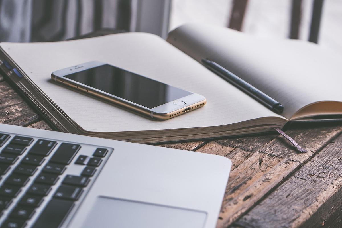 Espace de travail avec laptop, téléphone et carnet sur surface en bois clair Espace de travail avec laptop, téléphone et carnet sur surface en bois clair