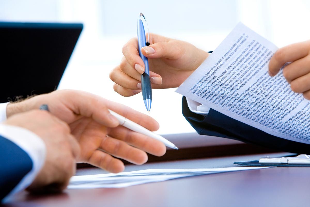 Deux personnes consultent des documents papier à un bureau professionnel, stylo en main Deux personnes consultent des documents papier à un bureau professionnel, stylo en main