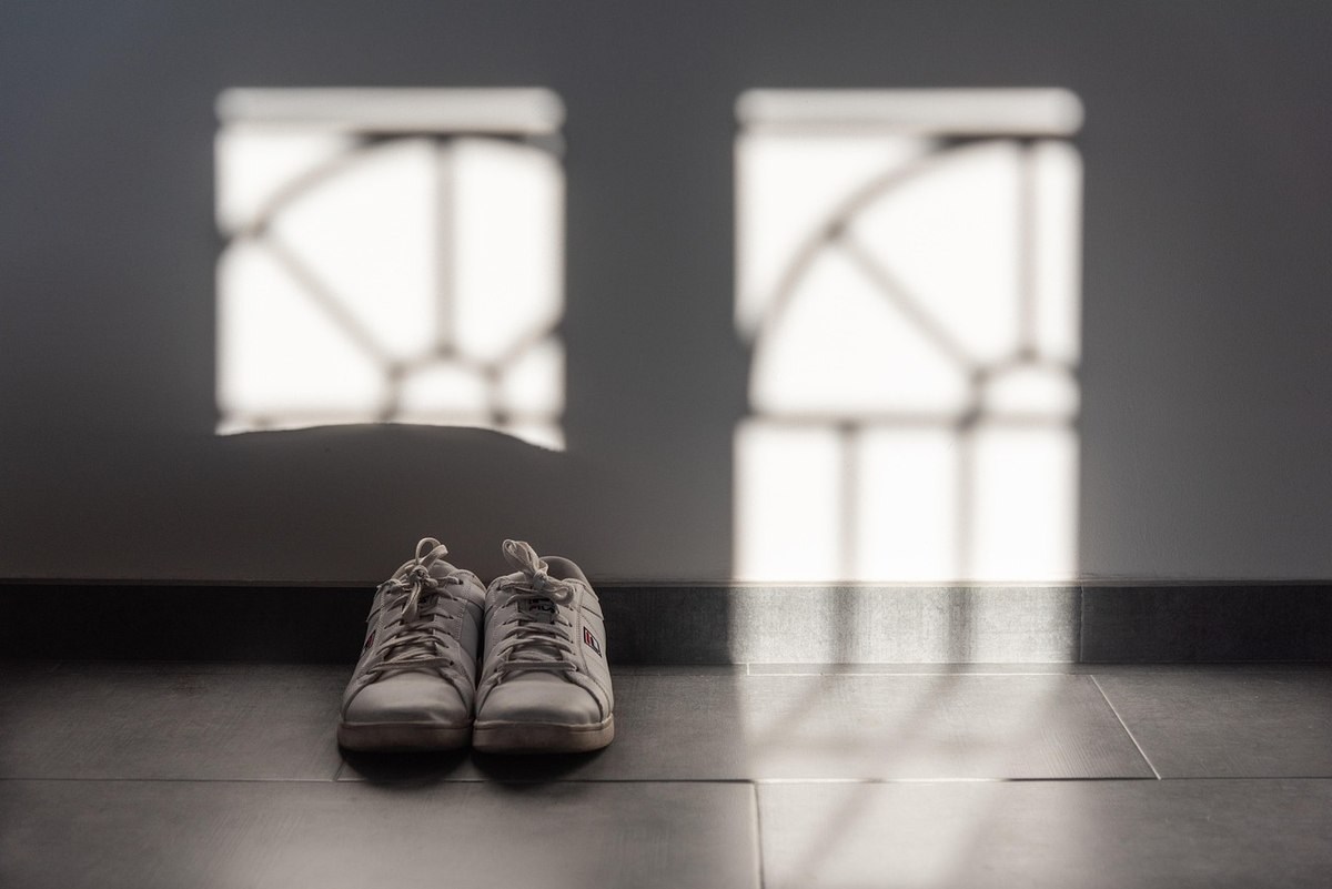 Chaussures blanches sur un sol gris devant des fenêtres avec motifs géométriques Chaussures blanches sur un sol gris devant des fenêtres avec motifs géométriques