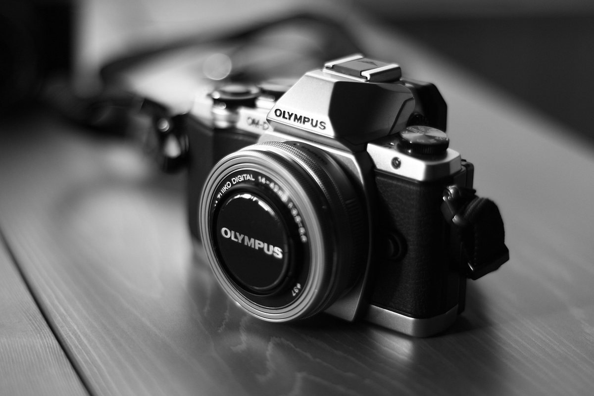 Appareil Olympus noir et argent sur une surface, flou en arrière-plan