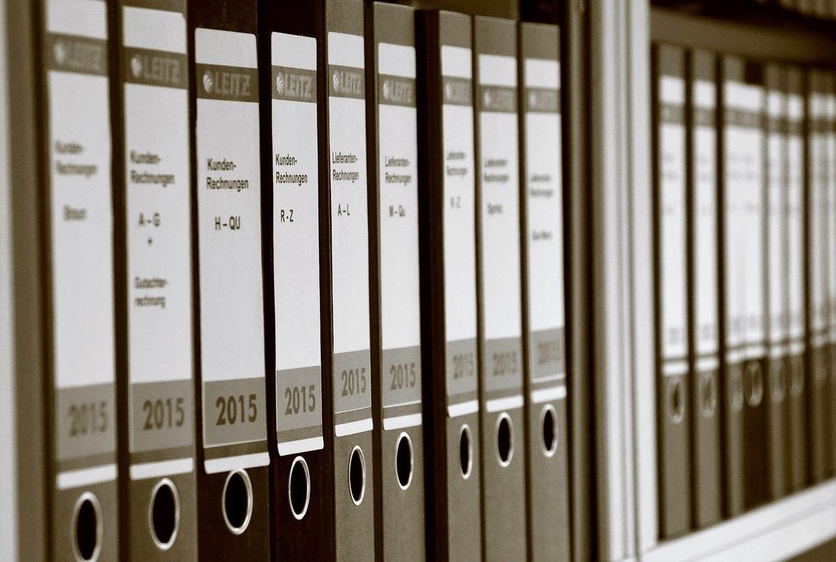 Des boîtes d'archives et des classeurs alignés sur une étagère de bureau. Des boîtes d'archives et des classeurs alignés sur une étagère de bureau.
