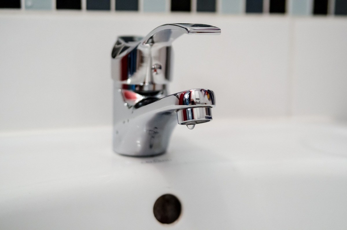 Robinet d'évier en chrome avec goutte d'eau, carrelage blanc, trou d'écoulement Robinet d'évier en chrome avec goutte d'eau, carrelage blanc, trou d'écoulement