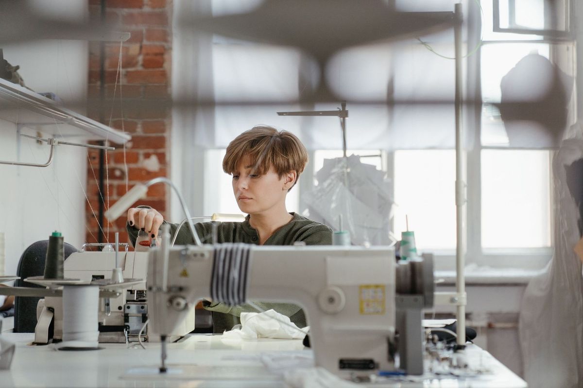 Jeune individu utilisant une machine à coudre dans un atelier lumineux