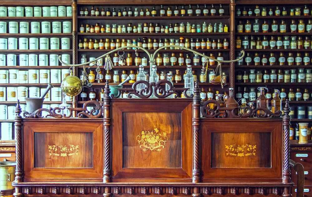 Étagères de médicaments, comptoir en bois, vitrines ornées, intérieur de pharmacie antique
