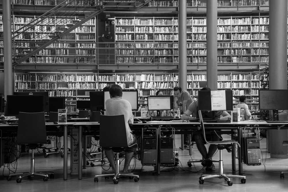 Salle de lecture d'une bibliothèque universitaire avec des étudiants travaillant sur des ressources numériques