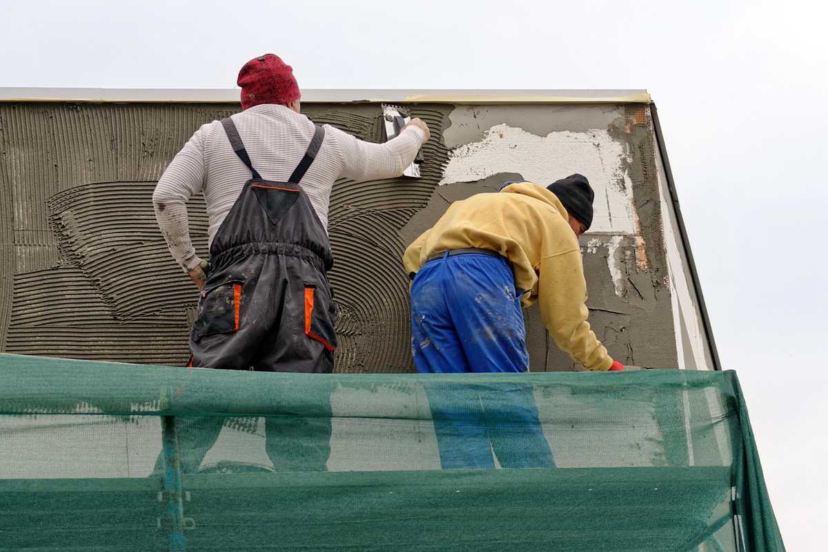 Deux ouvriers travaillent sur la rénovation d'une façade ancienne avec échafaudage Deux ouvriers travaillent sur la rénovation d'une façade ancienne avec échafaudage