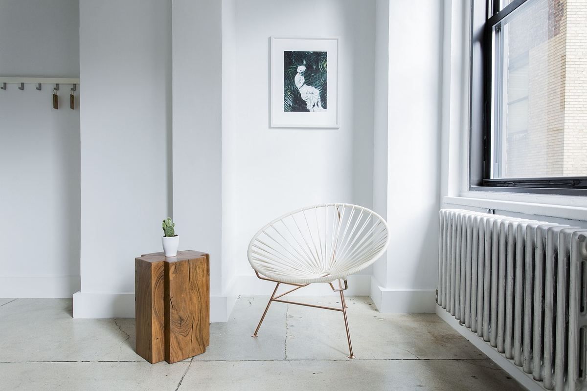 Un intérieur minimaliste avec un fauteuil blanc, une table en bois et une petite plante