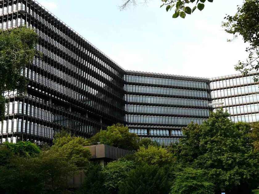 Bâtiment moderne avec façade vitrée et structure métallique, intégré à un environnement verdoyant Bâtiment moderne avec façade vitrée et structure métallique, intégré à un environnement verdoyant