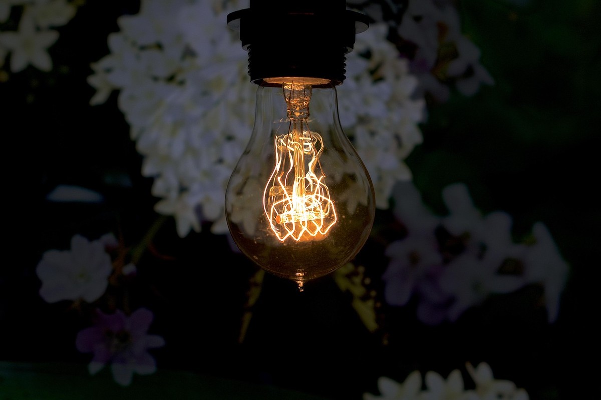 Ampoule incandescente allumée suspendue, émettant une lumière chaude dorée dans l'obscurité