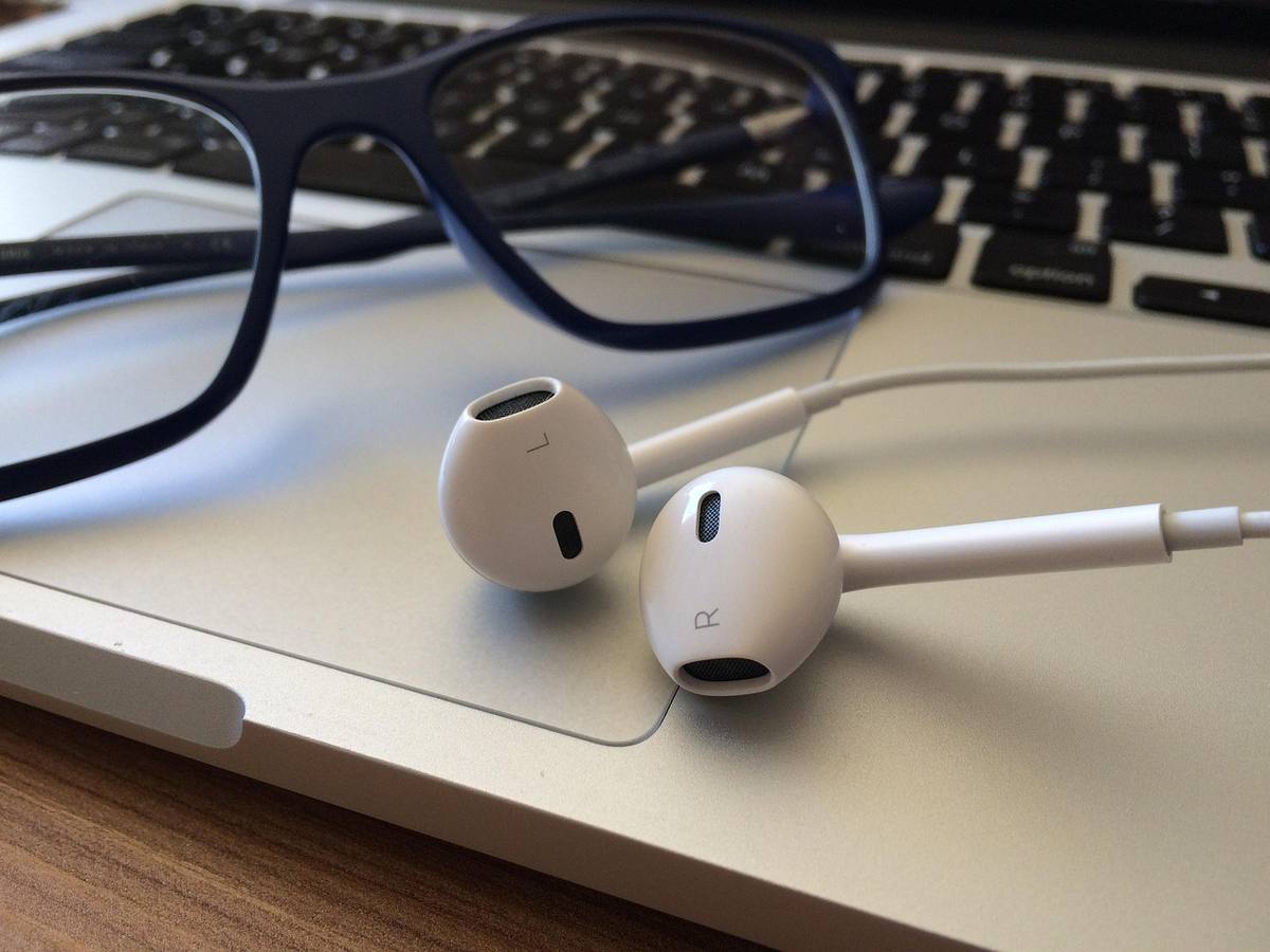 Des écouteurs sans fil sont posés sur un bureau, symbolisant une écoute de podcast en mobilité sans friction. Des écouteurs sans fil sont posés sur un bureau, symbolisant une écoute de podcast en mobilité sans friction.