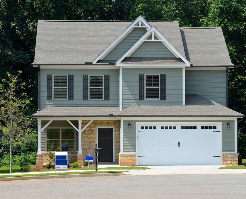 Maison verte à deux étages avec toit gris et garage blanc