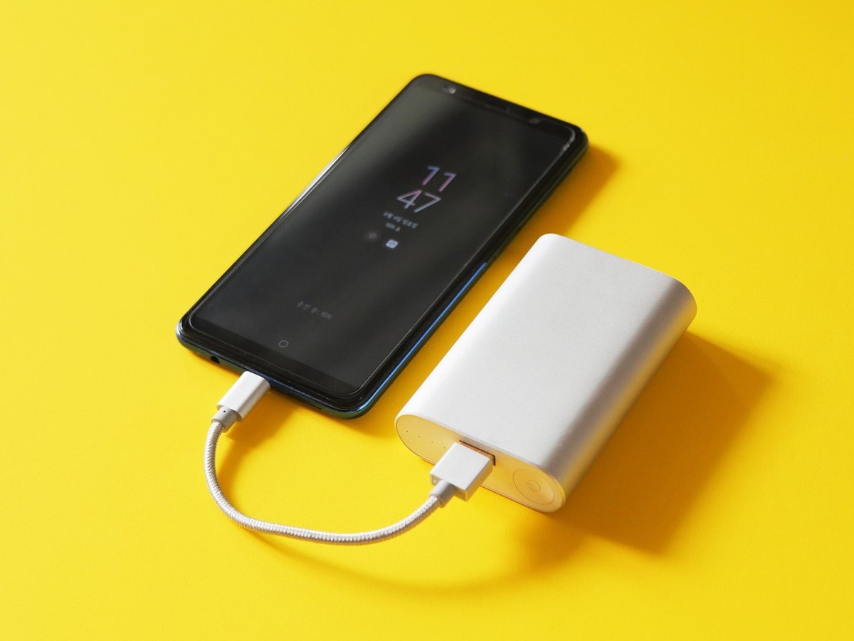 Deux batteries externes, une noire et une blanche, connectées ensemble sur fond jaune Deux batteries externes, une noire et une blanche, connectées ensemble sur fond jaune