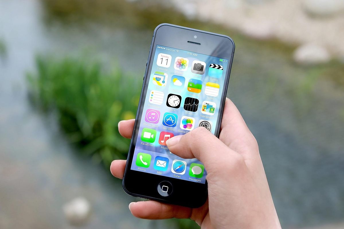 Mains tenant un smartphone affichant une page de réservation d’hôtel