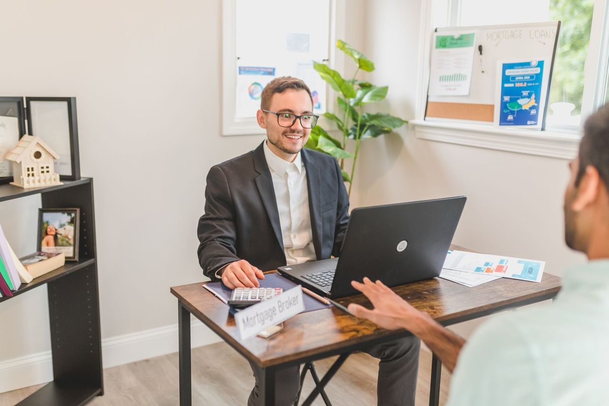 Homme en costume et homme en chemise blanche discutant autour d'un ordinateur portable dans un bureau décoré Homme en costume et homme en chemise blanche discutant autour d'un ordinateur portable dans un bureau décoré