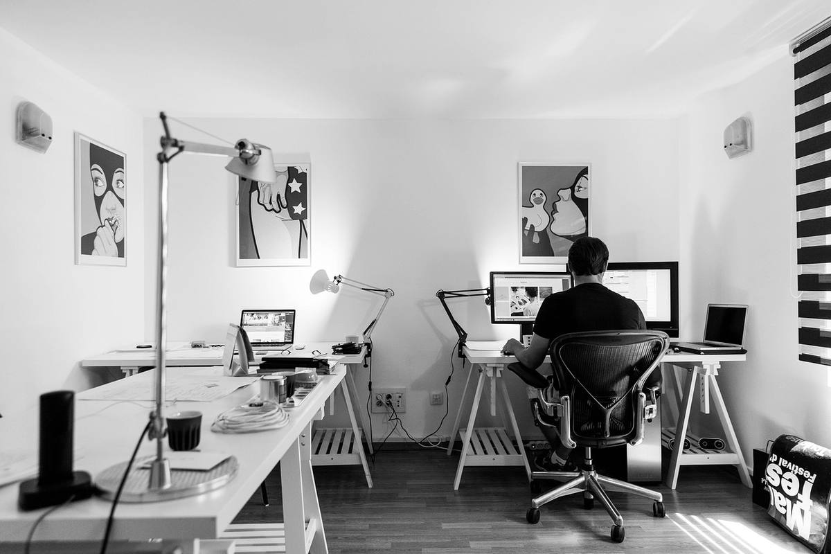 Bureau blanc minimaliste avec deux personnes assises aux bureaux devant leurs écrans d'ordinateur