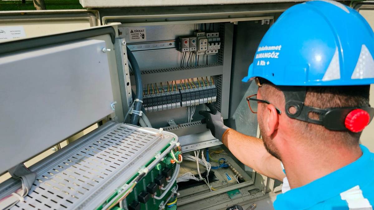 Technicien en bleu examine un tableau électrique ouvert
