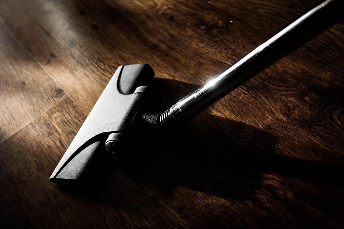 Aspirateur noir sur parquet en bois, lumière et ombre