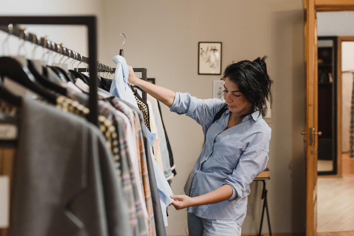 Femme sélectionne un vêtement sur une perche dans un dressing