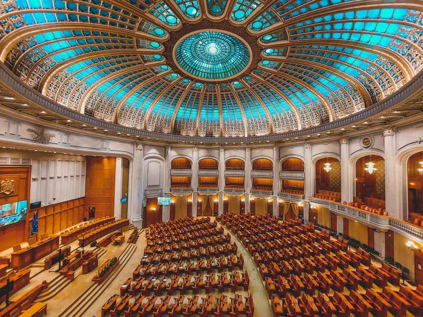 Intérieur d'une salle de concert avec orgue, sièges, balcon, dôme lumineux, murs ornés, chandeliers, escaliers, portes