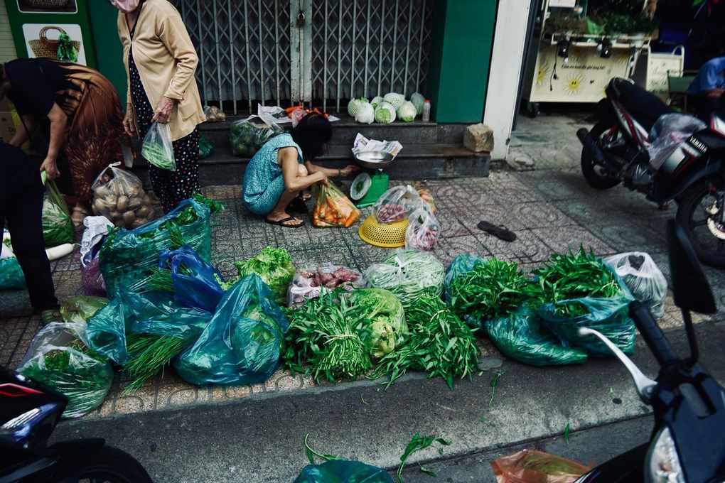 Marché de légumes sur trottoir avec sacs plastiques et vélos stationnés