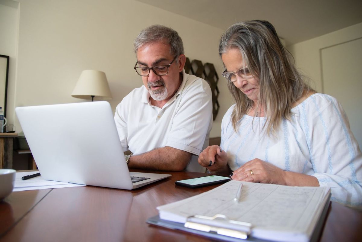Deux personnes âgées consultent un ordinateur portable à une table