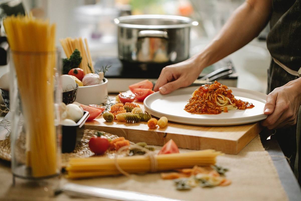 Chef assiette des pâtes sur une table de cuisine Chef assiette des pâtes sur une table de cuisine