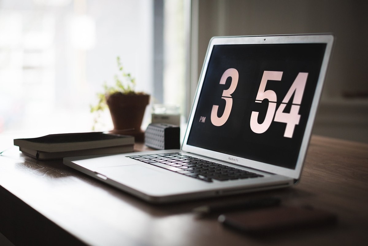 Un ordinateur portable sur un bureau affichant l'heure 3h54