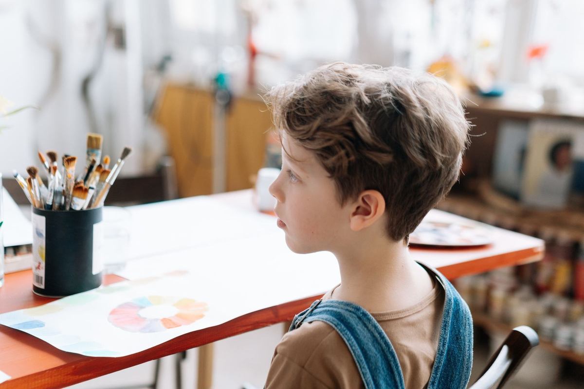 Enfant devant une table avec des pinceaux et des fournitures artistiques