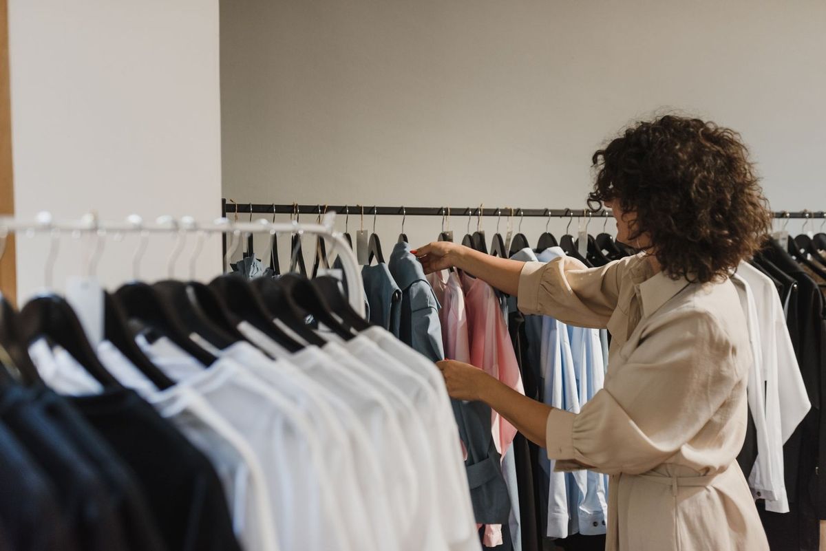 Femme examine des chemises sur des cintres dans une boutique Femme examine des chemises sur des cintres dans une boutique