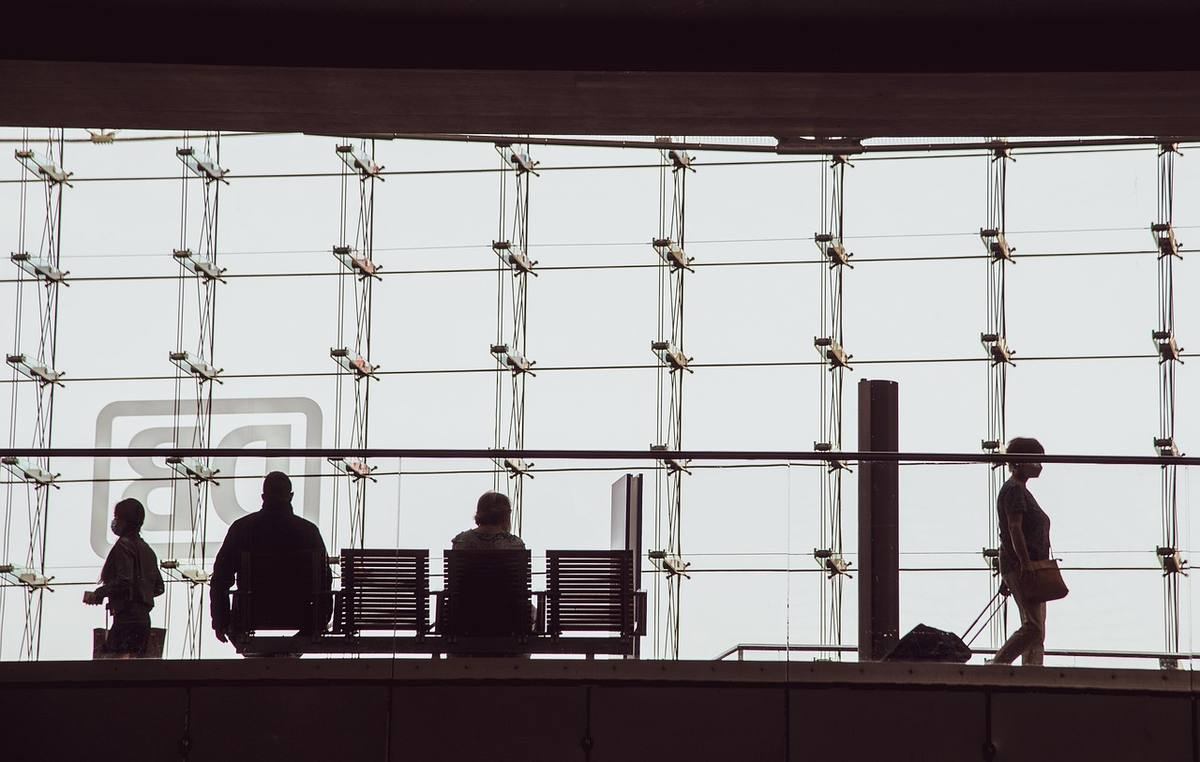 Silhouettes de personnes debout et assises devant une grande baie vitrée dans un espace professionnel lumineux