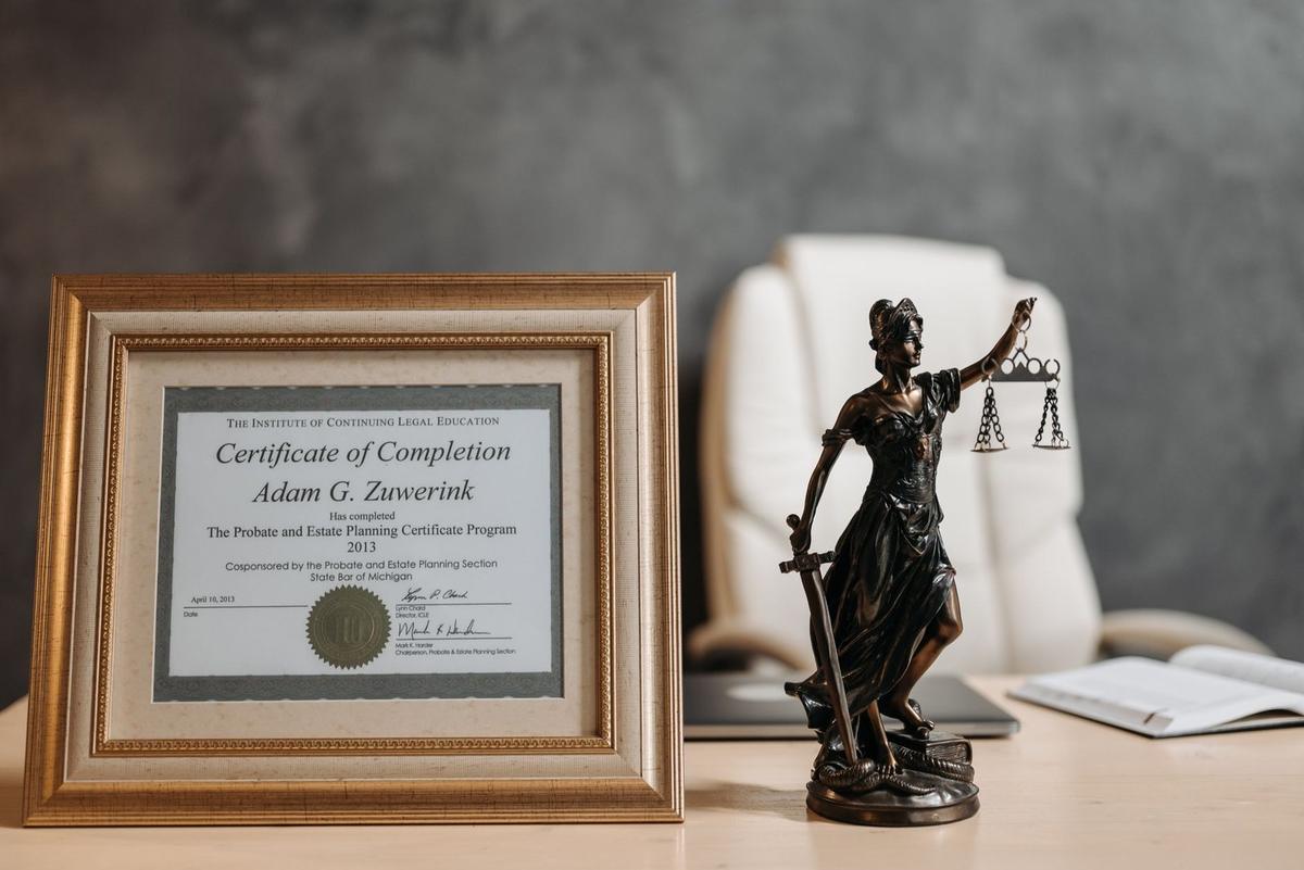 Certificat de complétion encadré à côté d'une statue de justice sur un bureau