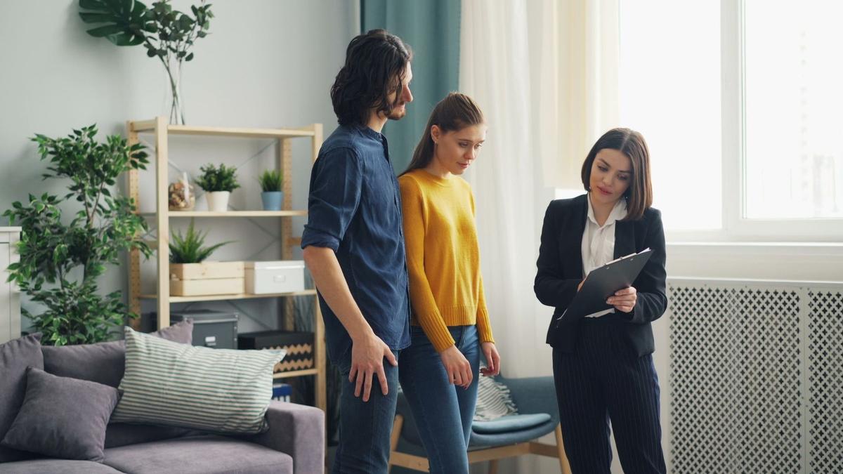 Trois personnes dans un salon, une avec un ordinateur portable Trois personnes dans un salon, une avec un ordinateur portable