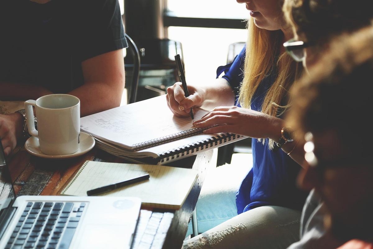 Deux personnes travaillent à un bureau avec ordinateur portable, documents et tasse de café