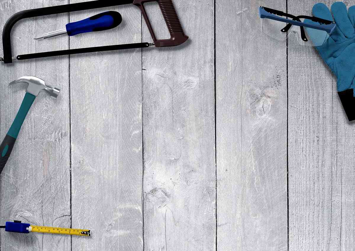 Tournevis, marteau, scie et autres outils disposés sur un plan de travail en bois clair Tournevis, marteau, scie et autres outils disposés sur un plan de travail en bois clair