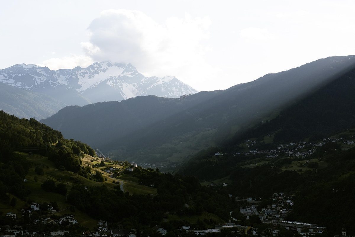 Vallées alpines avec villages nichés entre montagnes boisées et sommets enneigés