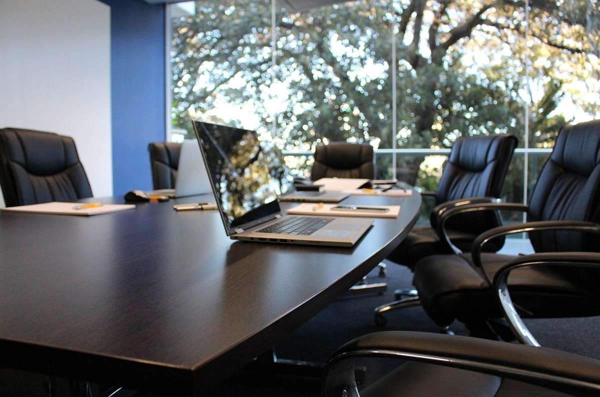 Salle de réunion avec table, ordinateurs, chaises, et vue sur les arbres à travers les fenêtres Salle de réunion avec table, ordinateurs, chaises, et vue sur les arbres à travers les fenêtres