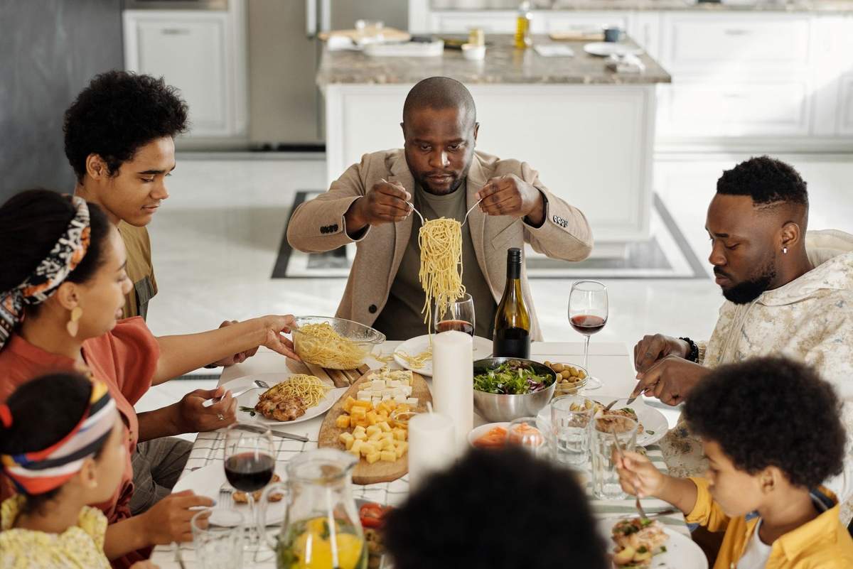Famille qui déjeune ensemble, assiette de pâtes, verres de vin sur la table