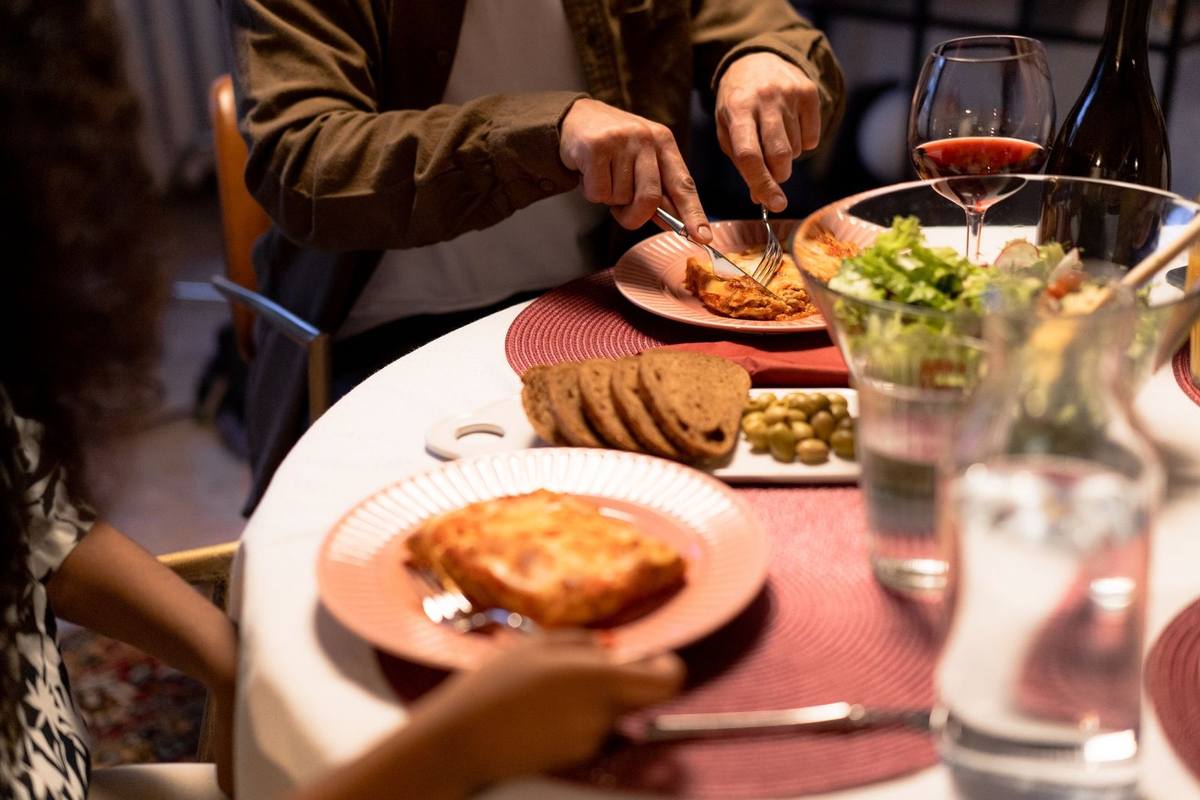 Personnes mangeant et buvant autour d'une table blanche avec assiette, verre et salade