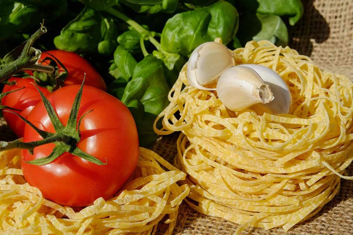 Tomates fraîches, pâtes sèches, laitue verte et œufs sur surface textile