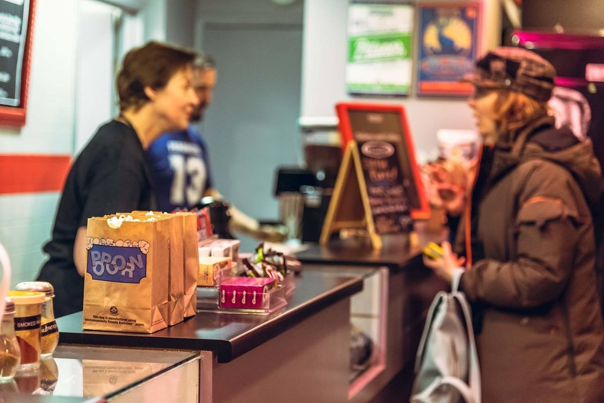 Femme en noir et femme en brun discutent derrière un comptoir de café Femme en noir et femme en brun discutent derrière un comptoir de café