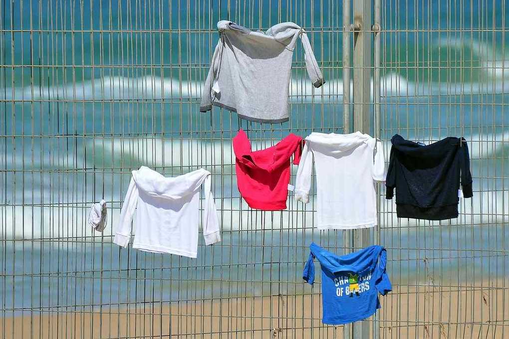 T-shirts de différentes couleurs sur une clôture près de la mer T-shirts de différentes couleurs sur une clôture près de la mer